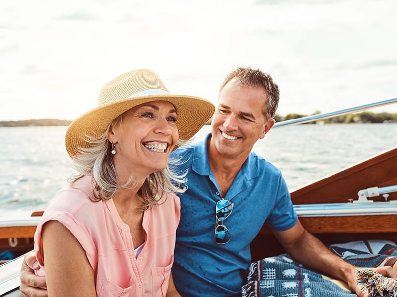 Albright Land & Development at Cedar Creek Lake | Man looks happily and woman as she laughs while riding along in a boat with lake in the background.