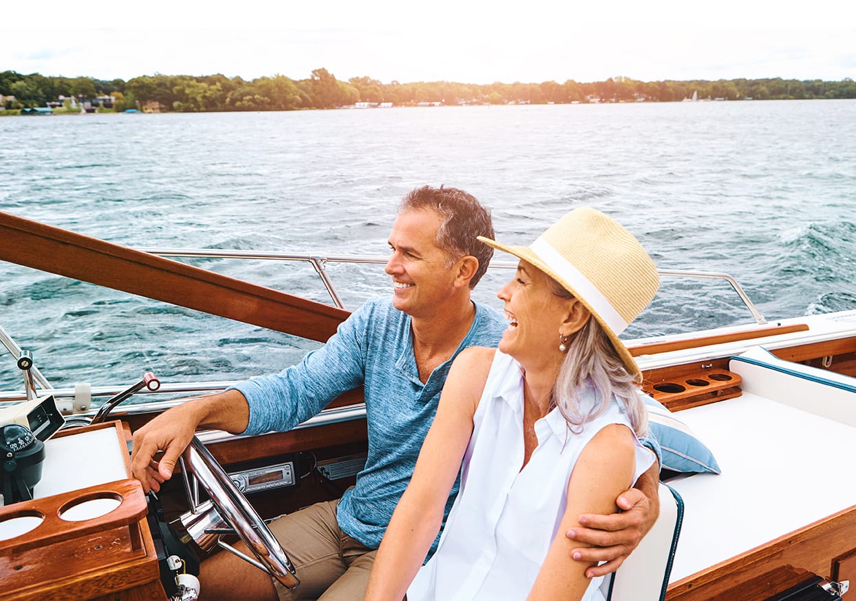 Albright Land & Development at Cedar Creek Lake | Woman laughs while man has arm around her while they cruise the lake on a sunny day.