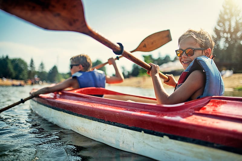 Albright Land & Development at Cedar Creek Lake | Two boys enjoying kayaking on lake on sunny summer day.